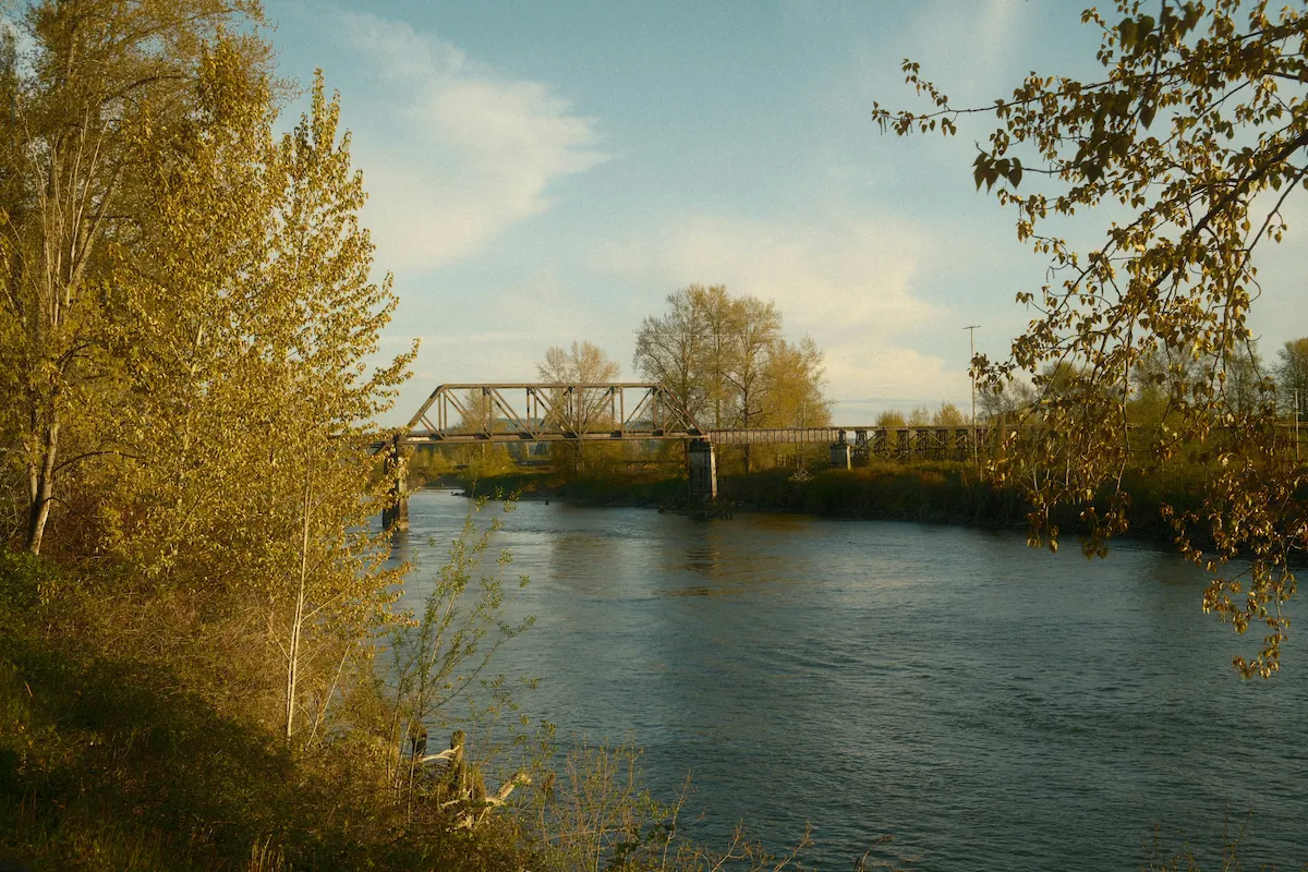 Snohomish County, Railroad bridge over tranquil river with autumn foliage.