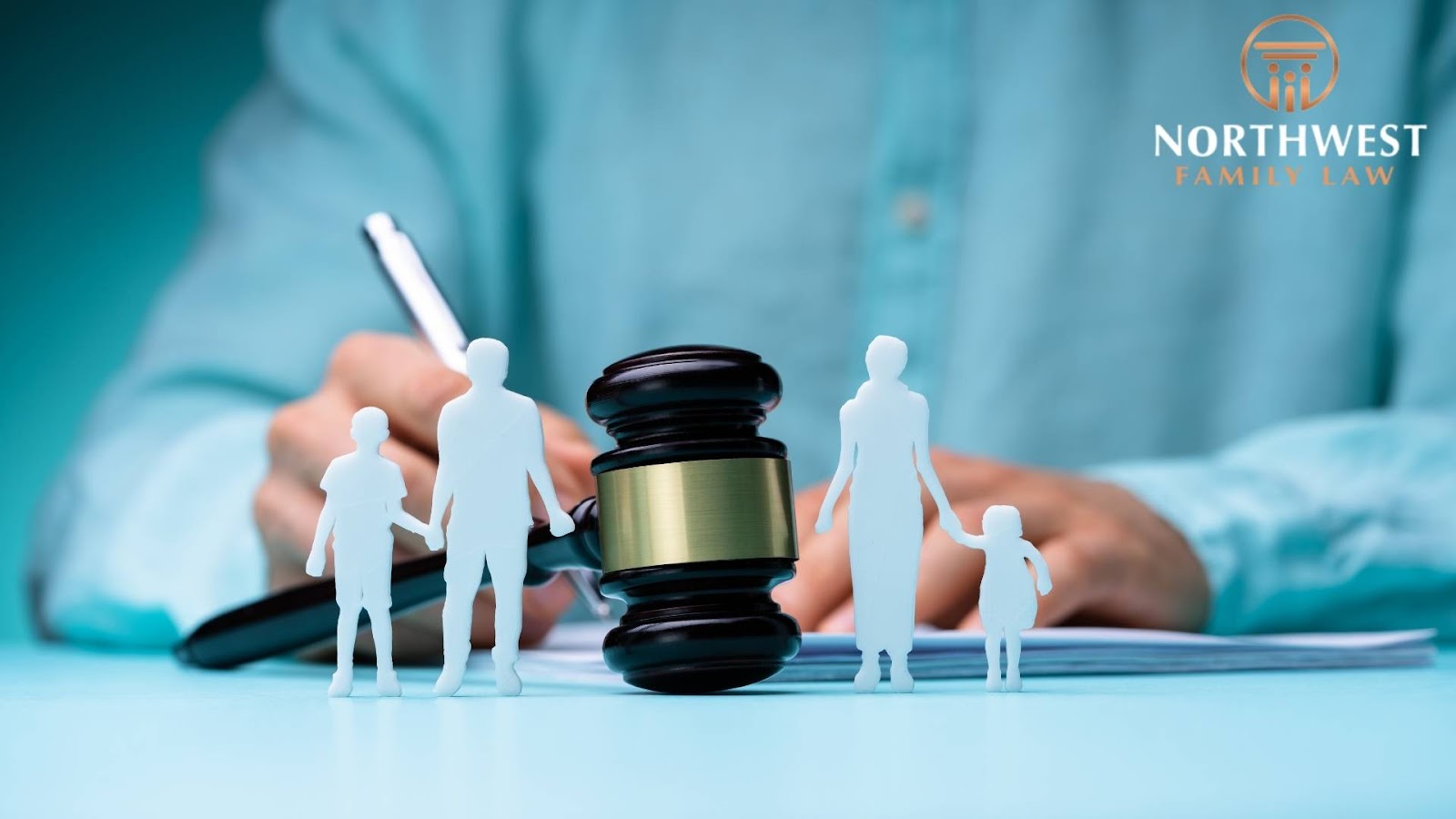 A legal professional in a blue shirt signs documents behind a gavel and cutout figures of a family, symbolizing custody or parenting plan decisions,