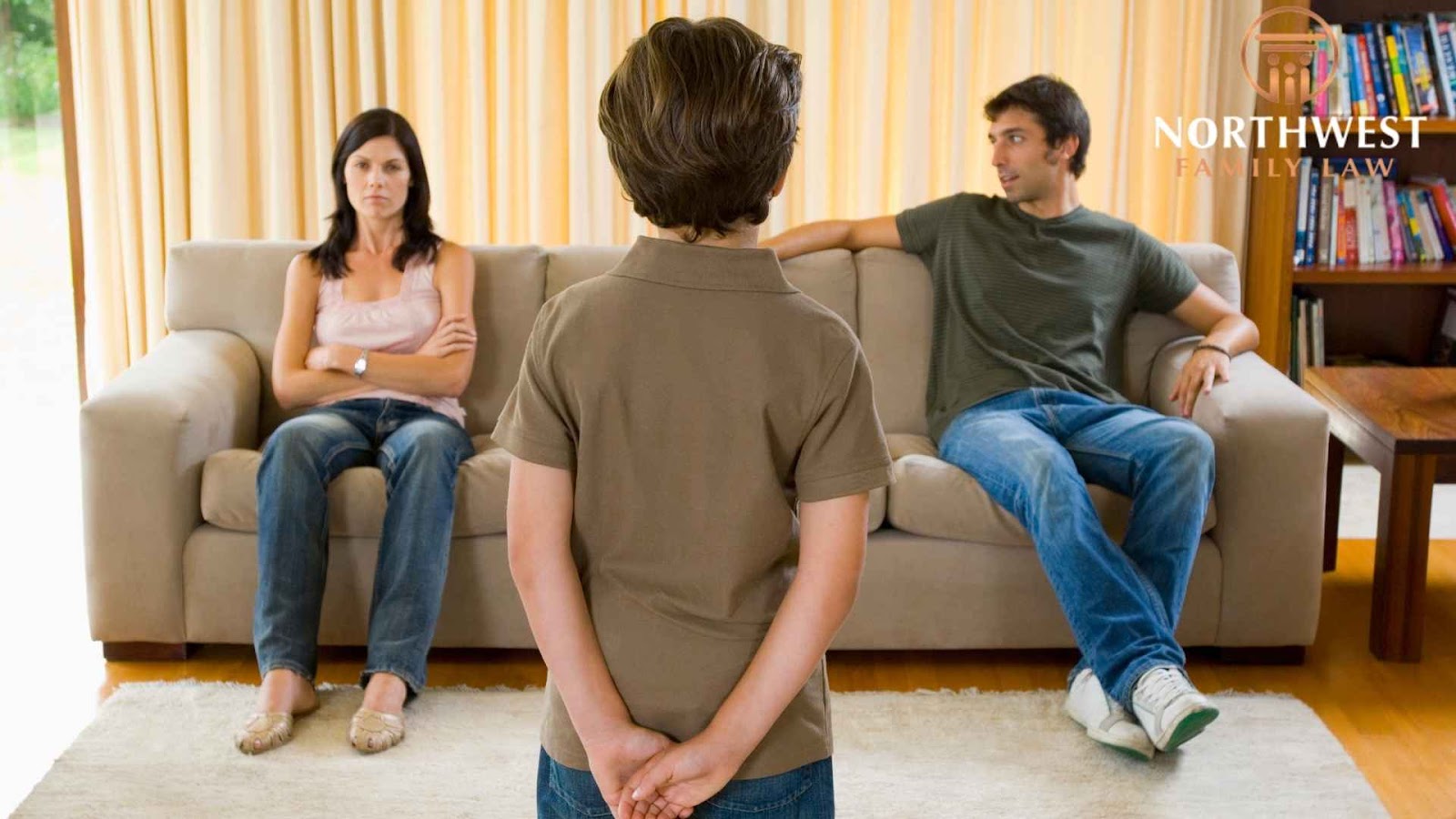 Child standing before parents on couch, serious discussion.