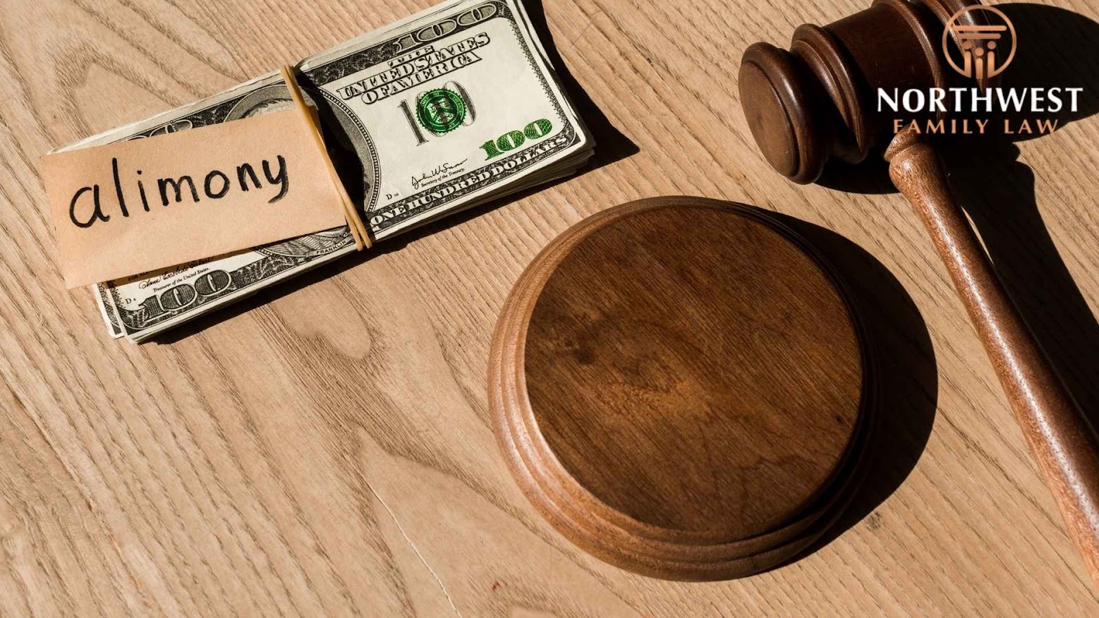 Alimony money with gavel on wooden table.