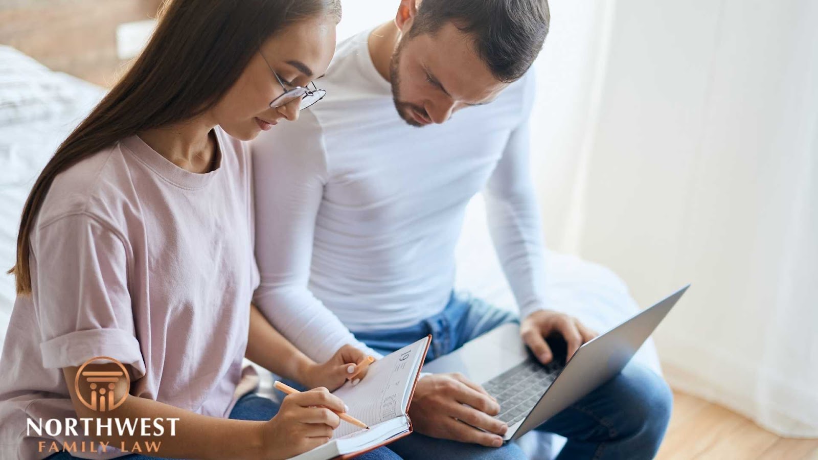 Couple reviewing documents with laptop and notebook.