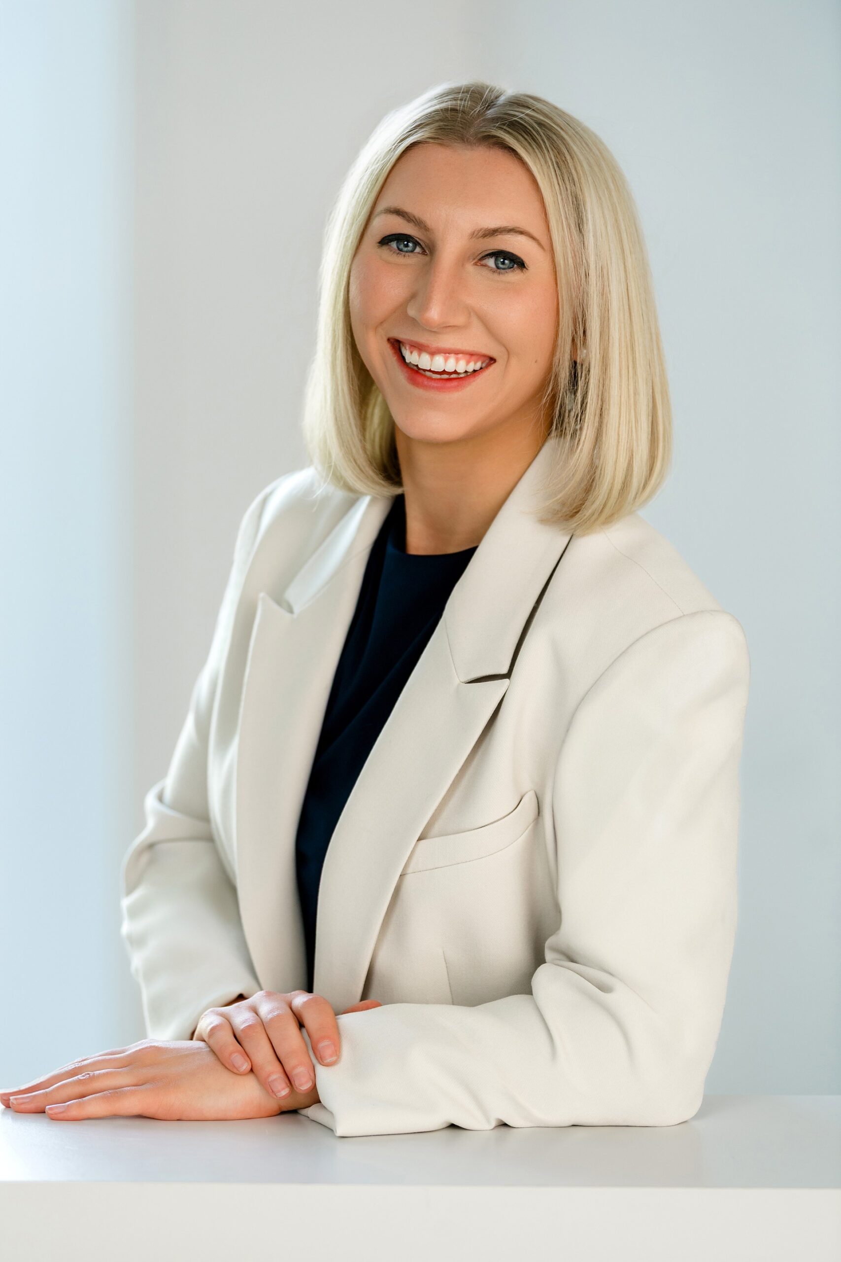 Smiling attorney in a white blazer posing confidently.
