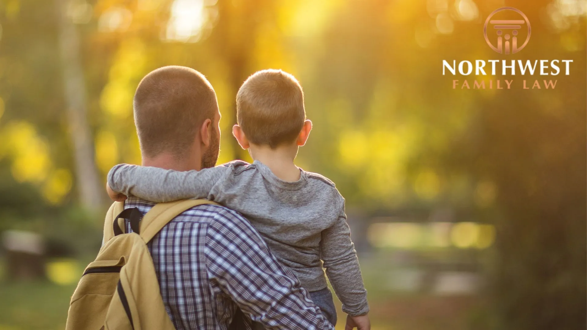 Father carrying son at sunset in park