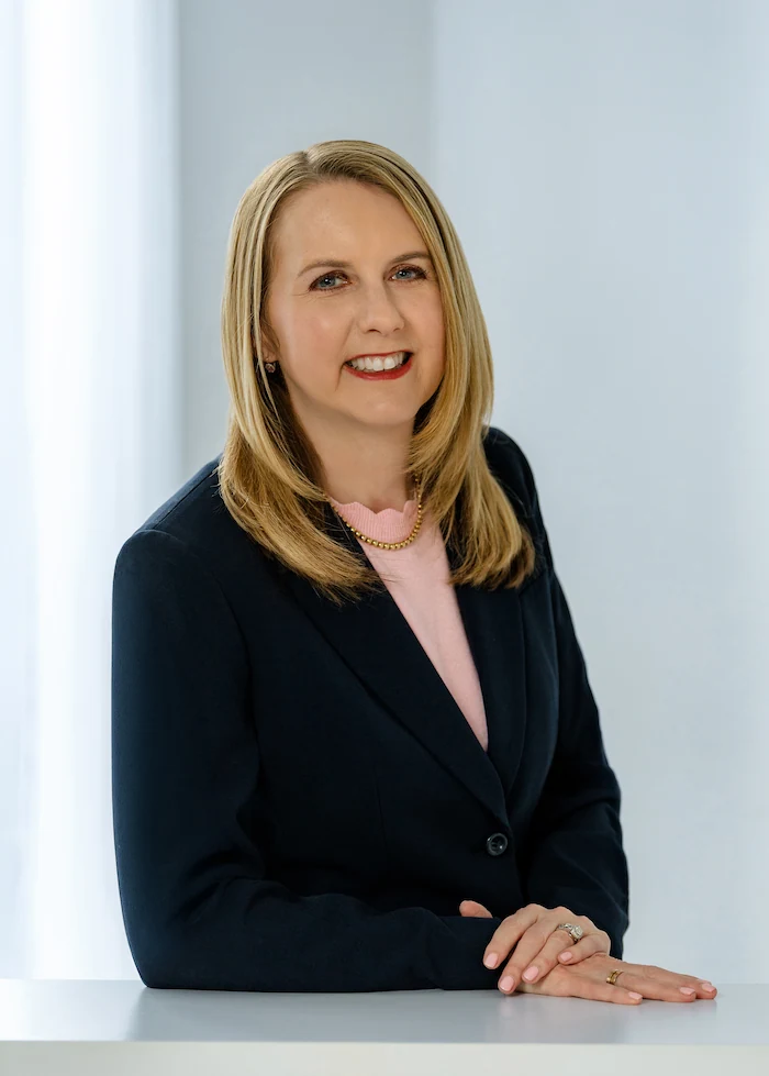 Professional woman in navy blazer smiling at camera