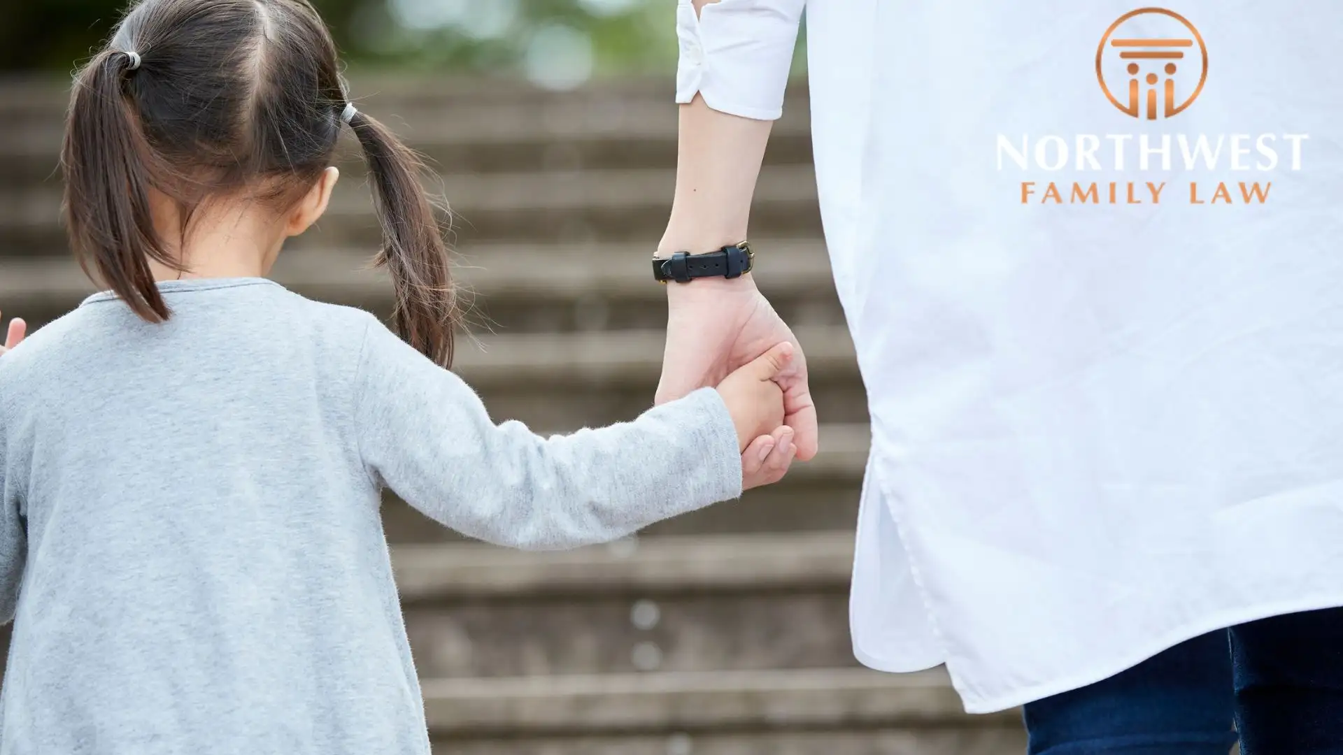 Child holding adult's hand on outdoor steps